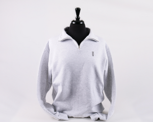 Close up of a grey quarter zip with a silver zipper and small brown wheat illustration on the left breast. 