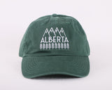 Green baseball cap with white embroidery on the front that says "ALBERTA" with wheat surrounding the base, and mountains framing the top