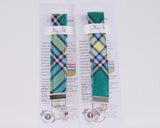 Two green plaid keychains with metal clips on a white background