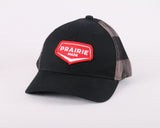 Black canvas ball cap with a red patch that reads "PRAIRIE MADE". The back of the ball cap has a grey and black plaid shell.